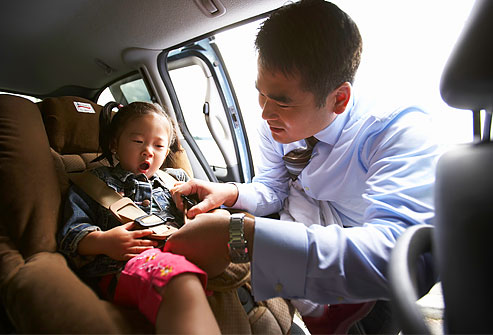 getty_rm_photo_of_father_buckling_daughter_into_car_seat